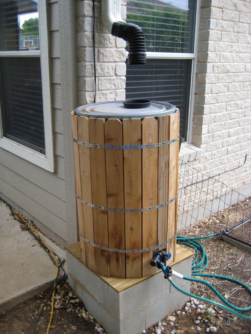 Rick’s rain barrel wrapped in cedar pickets under a downspout.